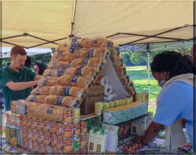 Two people working to build a tower of cans.