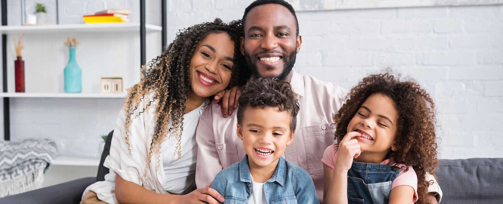 Family of four smiling in their living room