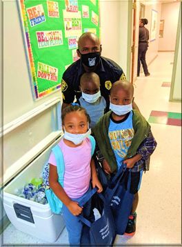 Three children with Greenville police officer at National Night Out event