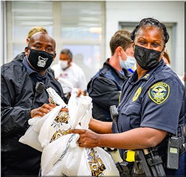 Two Greenville police officers handing out bags at National Night Out event.