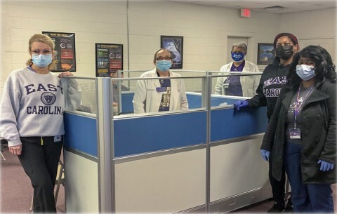 Women in masks posing at a Vaccine Clinic.