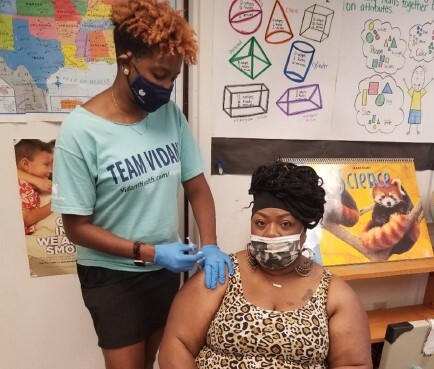  A woman administering a vaccine to another woman.