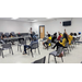 A group of people in a classroom with their hands raised.