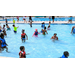 Numerous children in swimsuits playing in a pool.