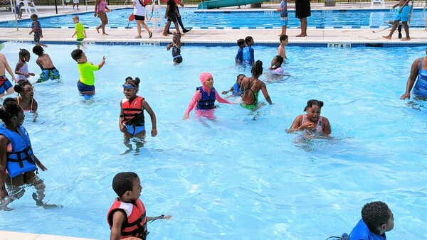 Numerous children in swimsuits playing in a pool.