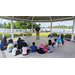 A group of students in a circle listening to a teacher talk. 