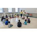 Children sitting in a circle listening to two women speak.