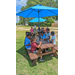 Children sitting at a picnic table beneath an umbrella.