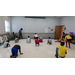 A classroom of children squatting down and working on their dance moves.