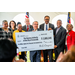 Multiple people standing on a stage receiving a large check. 