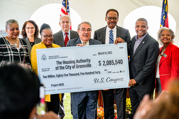 Multiple people standing on a stage receiving a large check. 