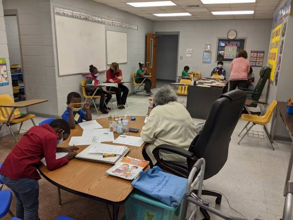 A teacher helping children with their homework at a table. 