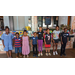 Children standing in a line showing off their artwork. 